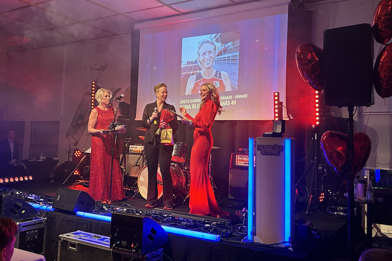 Tre kvinnor på scenen. En tar emot ett pris