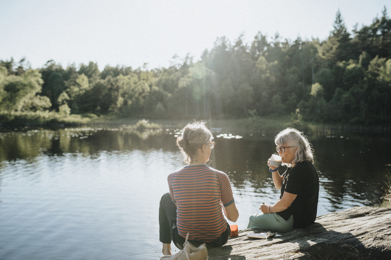 Kvinnliga pension&auml;rer p&aring; hajk sitter p&aring; klippa och dricker kaffe