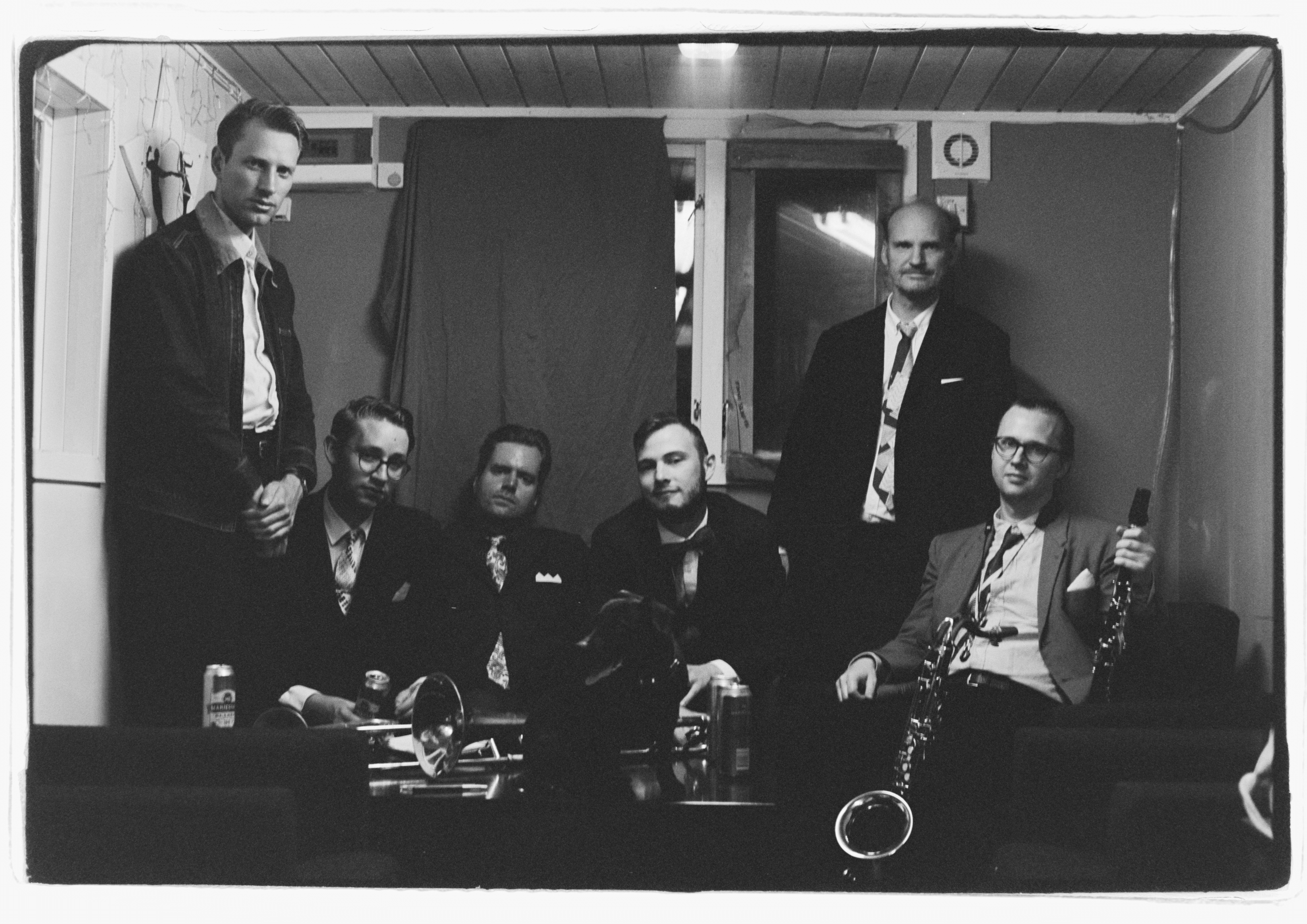 Sex killar och deras instrument som sitter och tittar in i kameran.