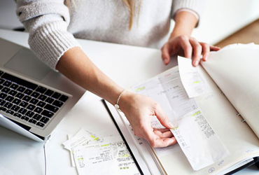 Händer bläddrar i pärm med räkningar