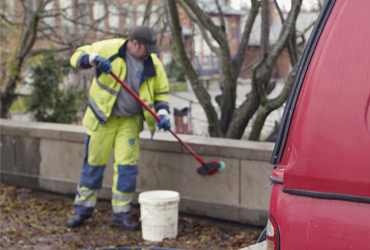 Människa i varselkläder klottersanerar en låg mur.