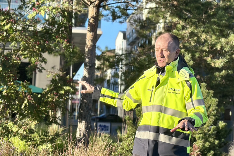En man i varseljacka st&aring;r bland klippor och tr&auml;d och pratar