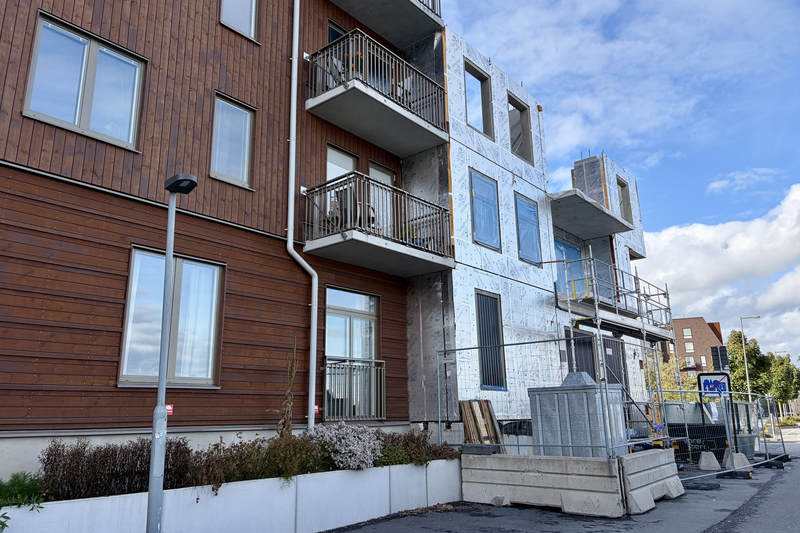 Flerbostadshus där halva huset är klart och halva huset håller på att byggas. Det är byggstaket runt det som håller på att byggas.