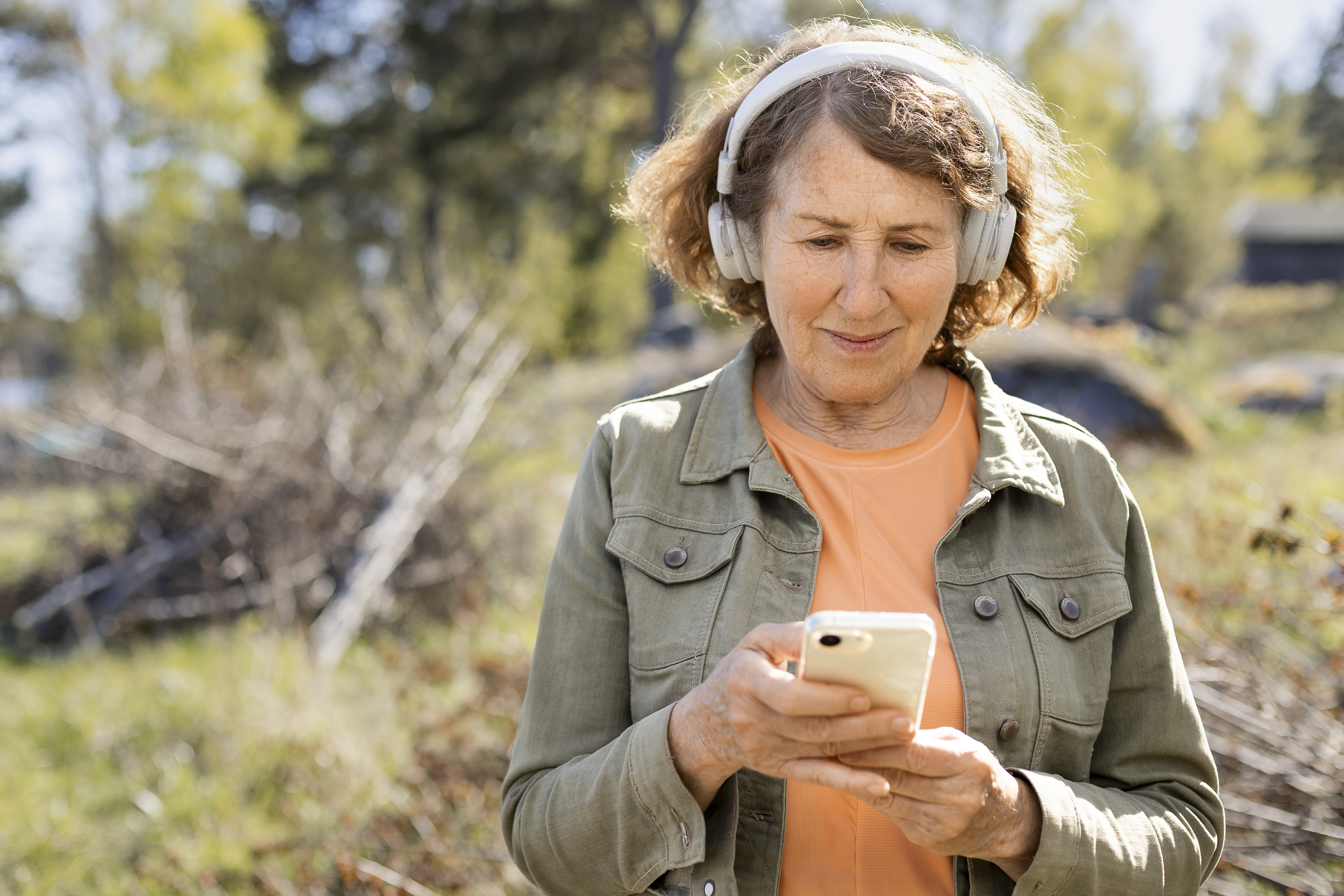 Kvinna som tittar på sin telefon och har hörlurar på sig