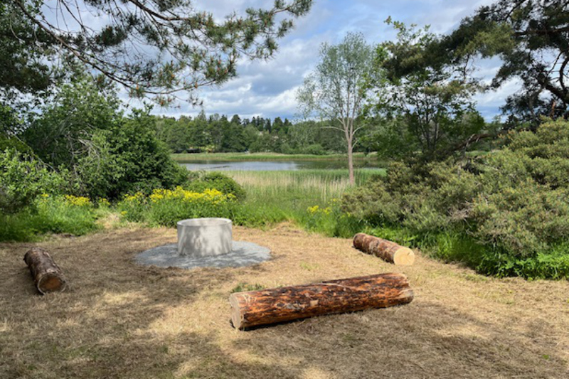 stockar runt en grillplats. I bakgrunden syns en sj&ouml; och gr&ouml;nska.