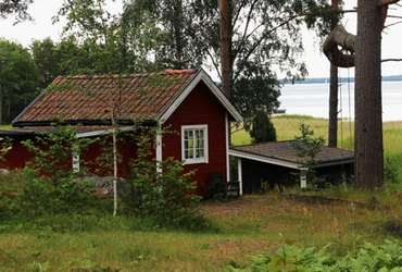 Röd liten sportstuga vid vattnet