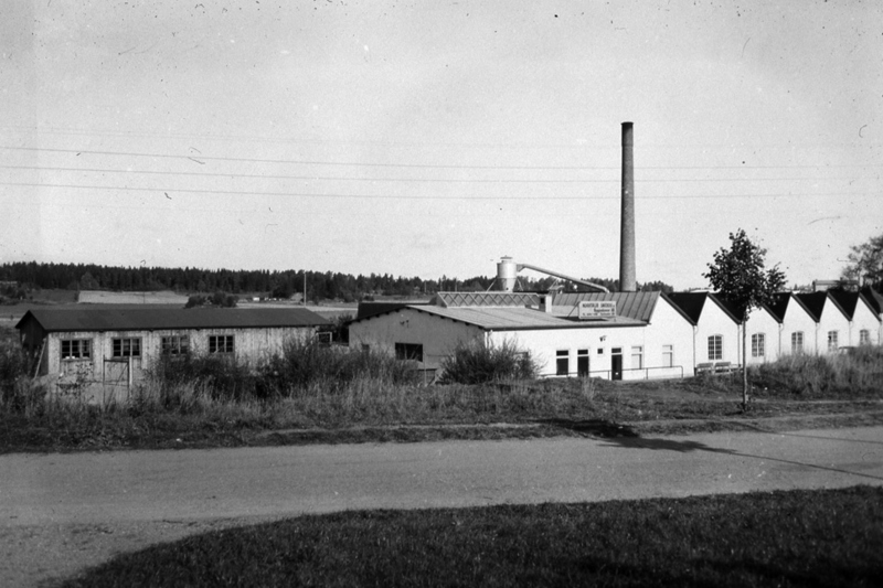 Norrt&auml;lje Snickerifabrik. En l&aring;g vitbyggnad med h&ouml;g skorsten