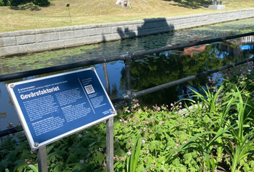 En blå skylt med texten Gevärsfaktoriet sitter vid Norrtäljeån