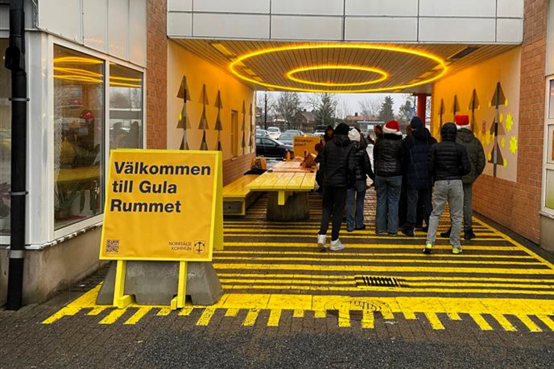 en tunnel med gulrandigt golv och gula dekorationer med massa m&auml;nniskor