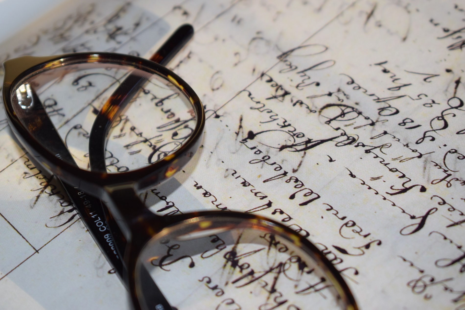 Glasögon som ligger på ett äldre dokument med handskriven text på