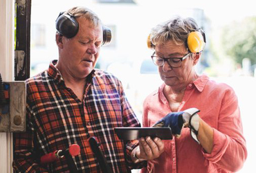 Senior couple discussing over digital tablet while standing at workshop doorway