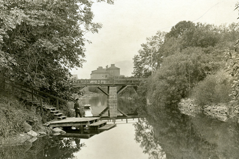 Landskapsbild. Norrt&auml;lje&aring;n med gr&ouml;nska runt om och en bro l&auml;ngre bort i bilden