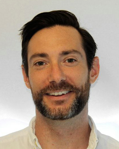 Porträttbild på en mörkhårig man med vit skjorta