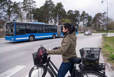 Kvinna på cykel väntar vid övergångsställe