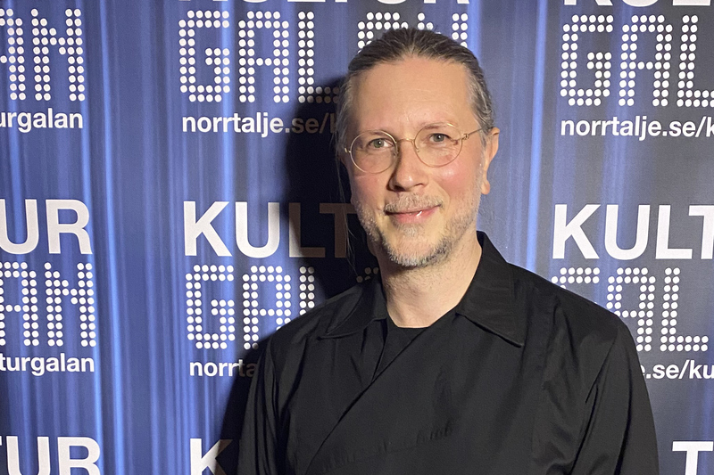 Anton Grandet iklädd en svart tröja står framför fotoväggen som är blå där det står Kulturgalan på.