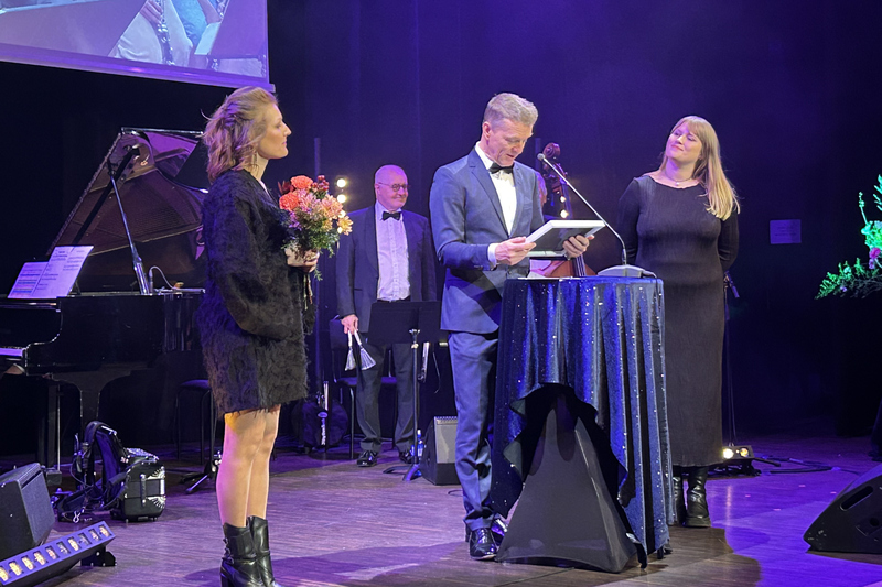 Kaisa Str&ouml;m i svart kl&auml;nning och blombukett i h&auml;nderna tilldelas pris.