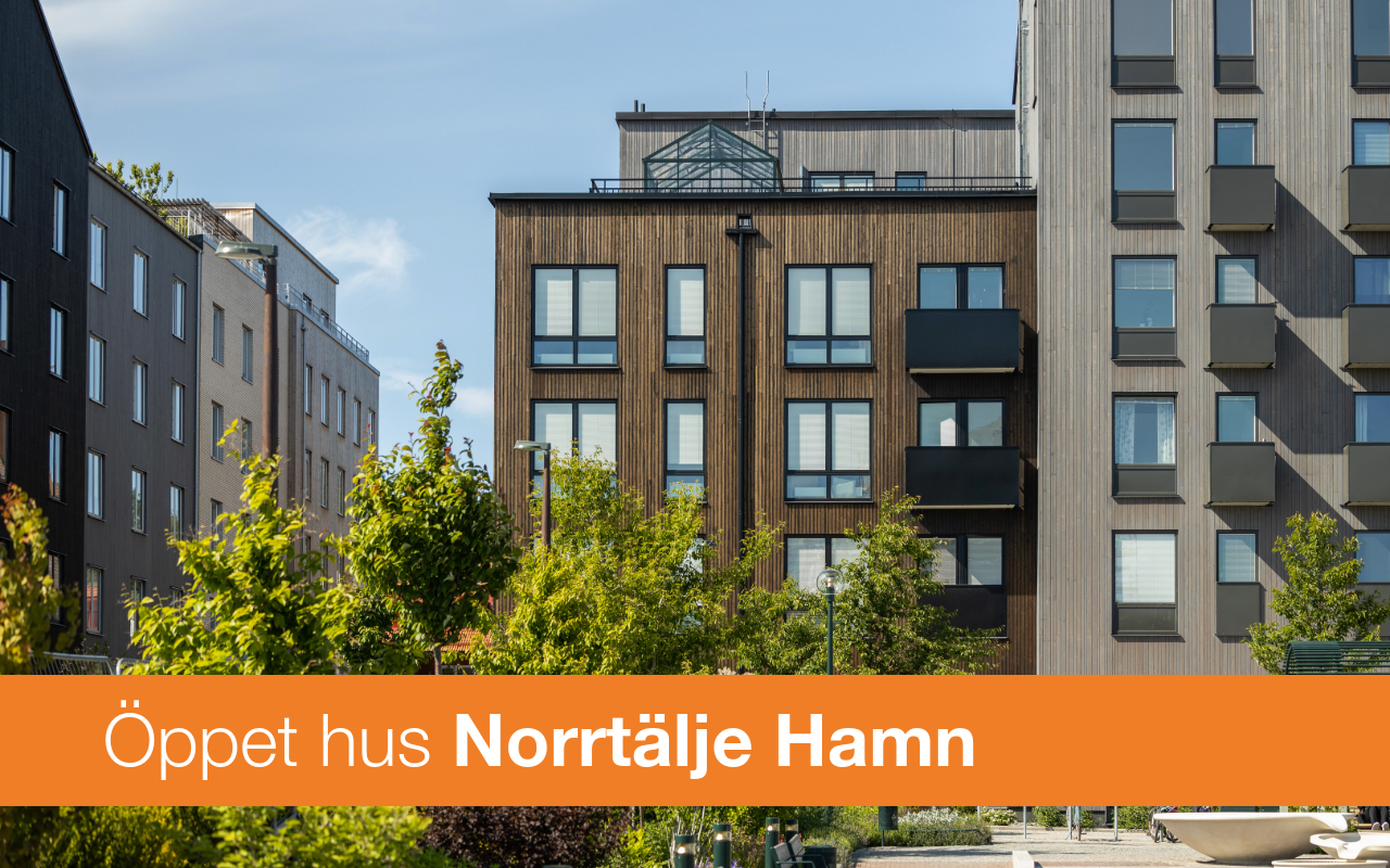 Ett flervåningshus och en orange platta med texten öppet hus norrtälje hamn