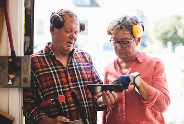 Senior couple discussing over digital tablet while standing at workshop doorway