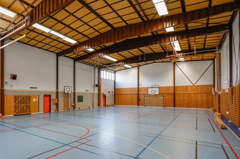 En sporthall inomhus med basketkorg och ribbstolar