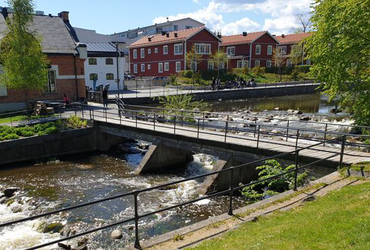 Bild med en bro över vatten och byggnader i bakgrunden