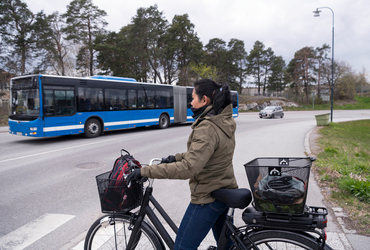 Kvinna på cykel väntar vid övergångsställe